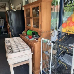 Binnenaanzicht van kringloopwinkel met houten meubels, opbergboxen en diverse spullen
