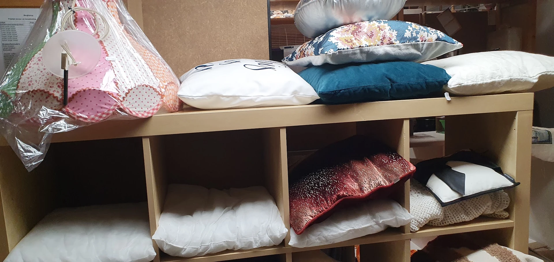 Houten stellingkast met kussens in verschillende kleuren en patronen uitgestald