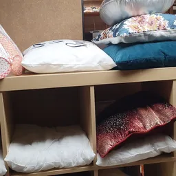 Houten stellingkast met kussens in verschillende kleuren en patronen uitgestald