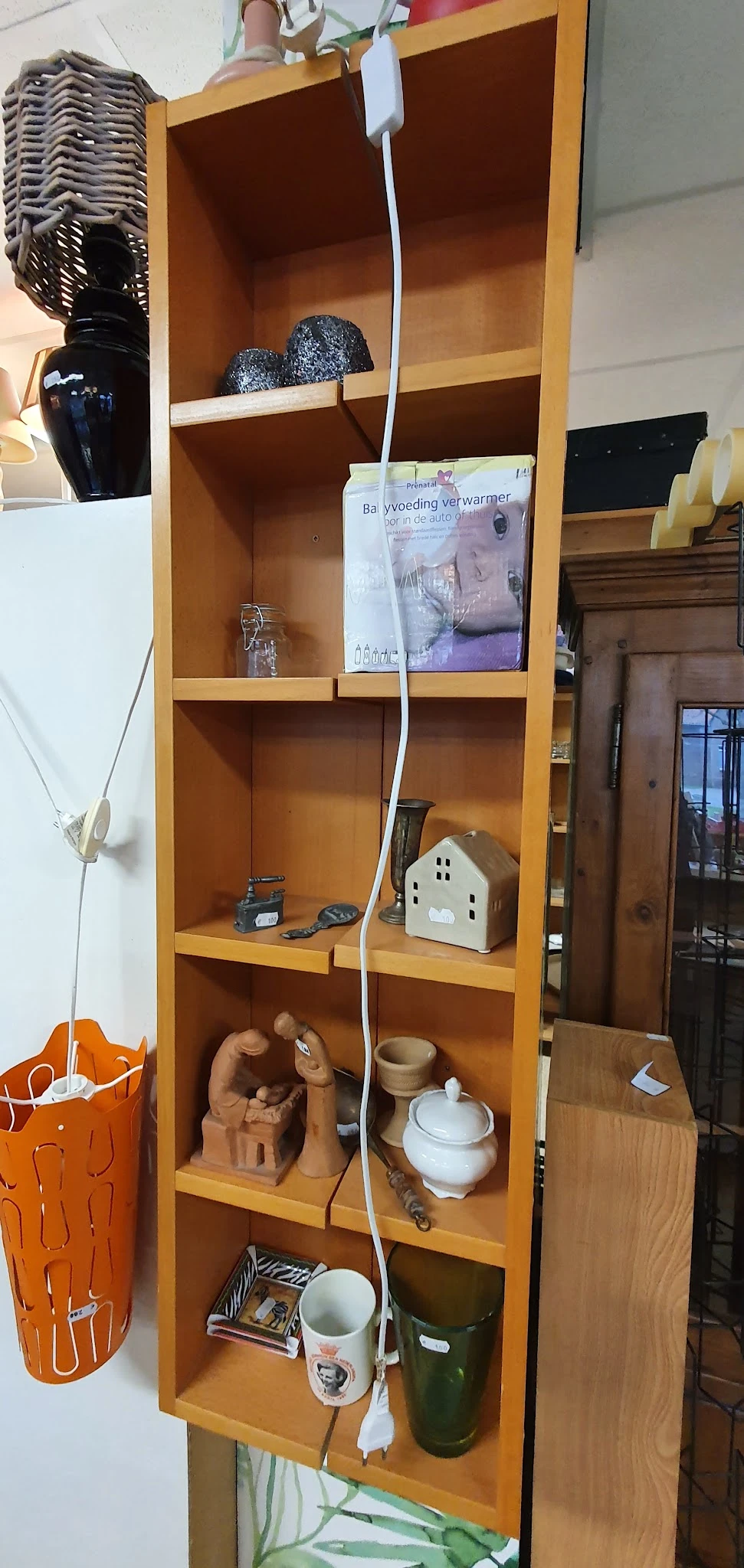 Houten wandkast met diverse huisraad en decoratieve items uitgestald op meerdere planken