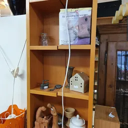 Houten wandkast met diverse huisraad en decoratieve items uitgestald op meerdere planken