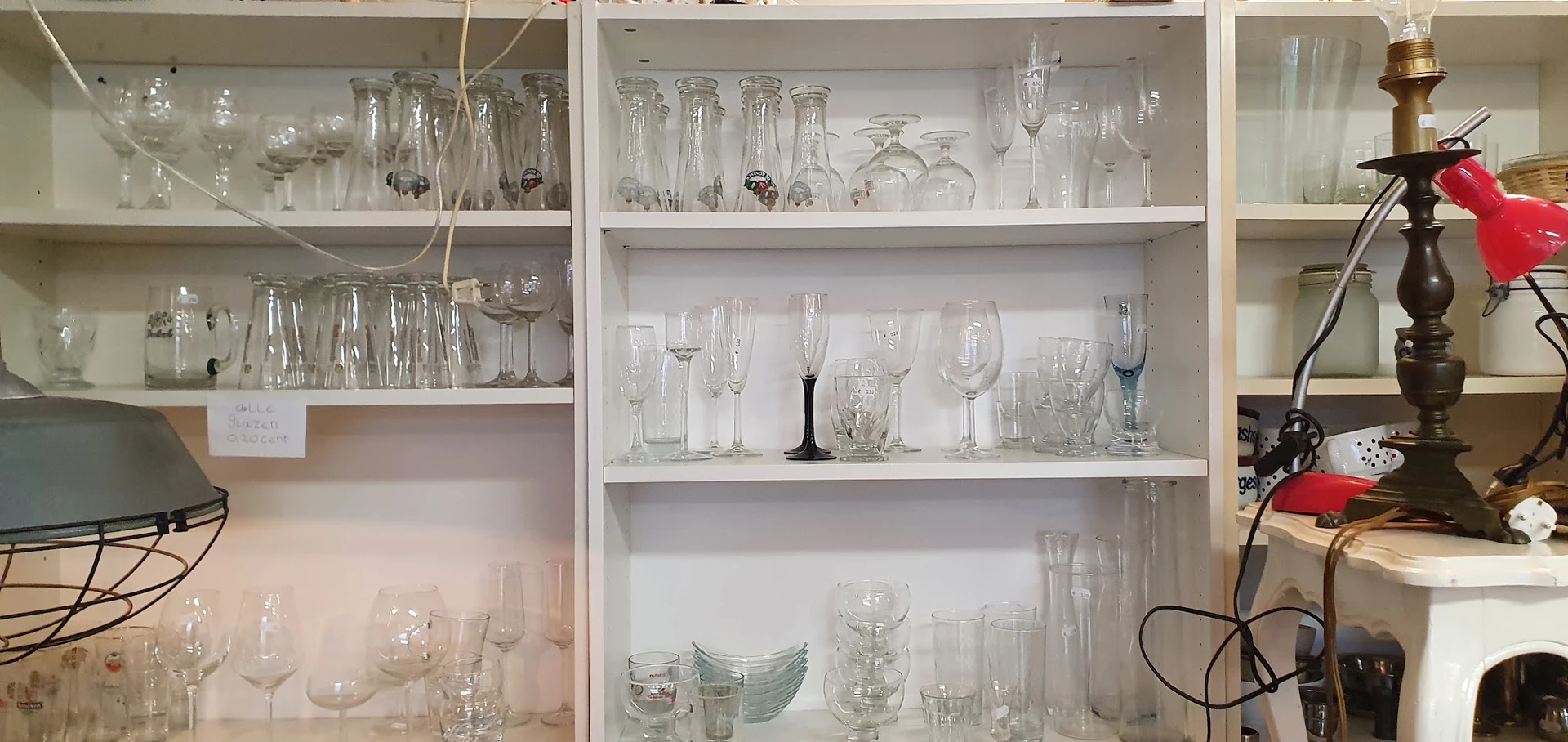 Glazenkast met diverse glazen en drinkglazen uitgestald op witte planken