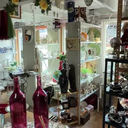 Glazen vitrinekasten met decoratieve items, vazen en verzamelobjecten in een kringloopwinkel