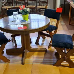 Ronde houten eettafel met vier stoelen met donkerblauwe zitting