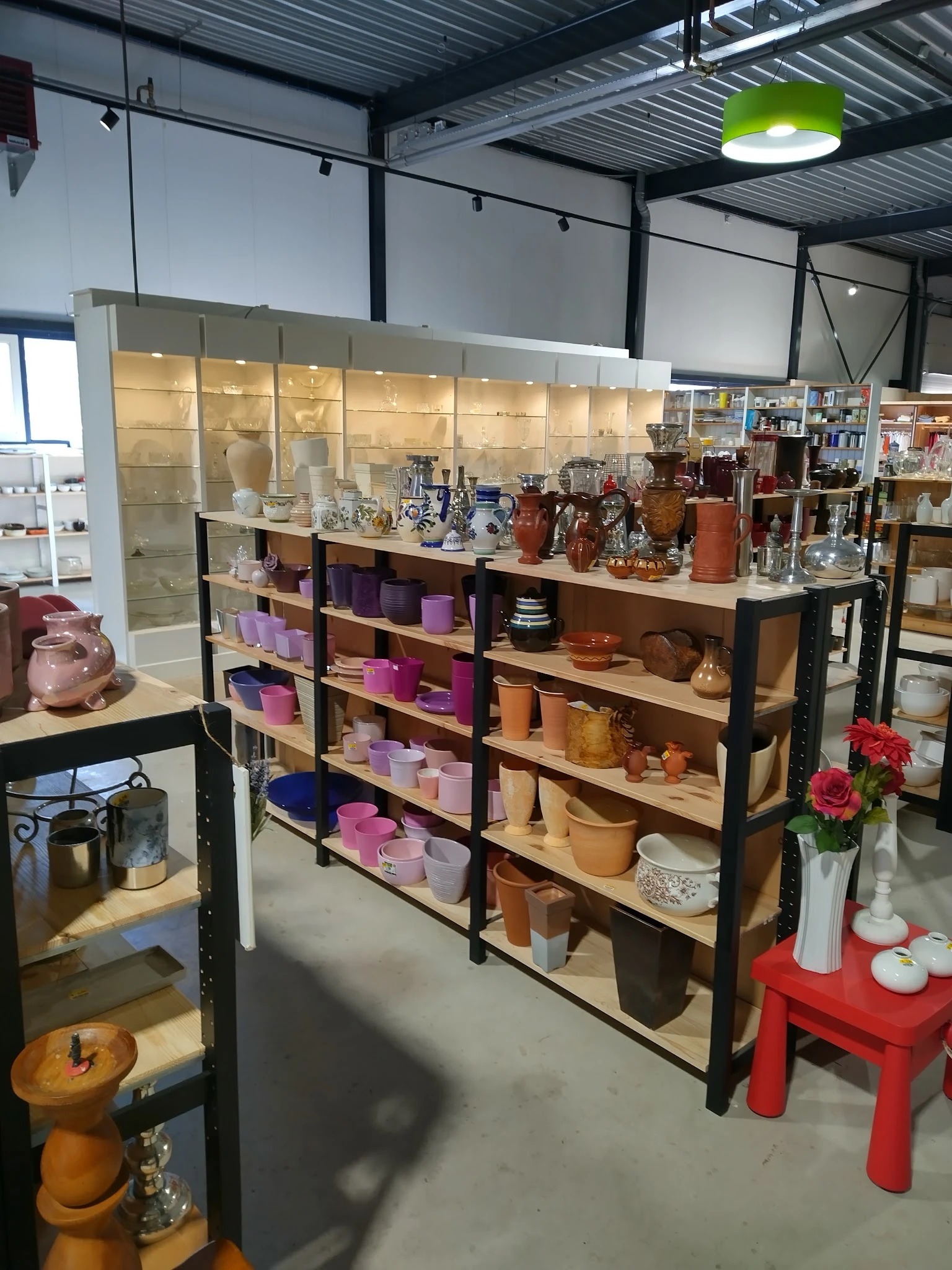 Stellingen met assortiment kaarsen, vazen en huishoudartikelen in verschillende kleuren en maten