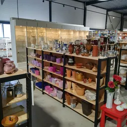 Stellingen met assortiment kaarsen, vazen en huishoudartikelen in verschillende kleuren en maten