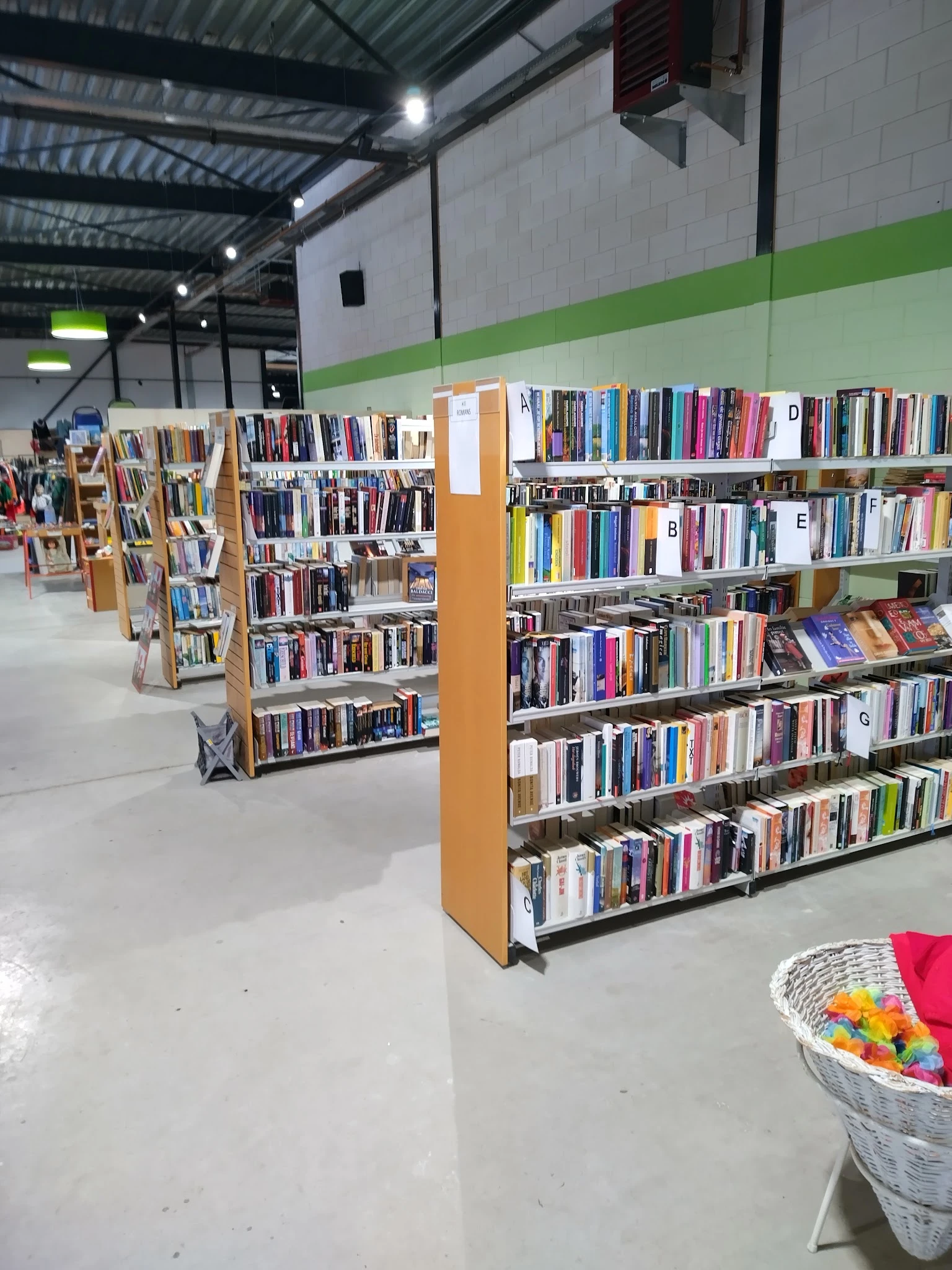 Boekenrekken met dvd's en cd's in de kringloopwinkel, met houten kasten en witte scheidingswanden