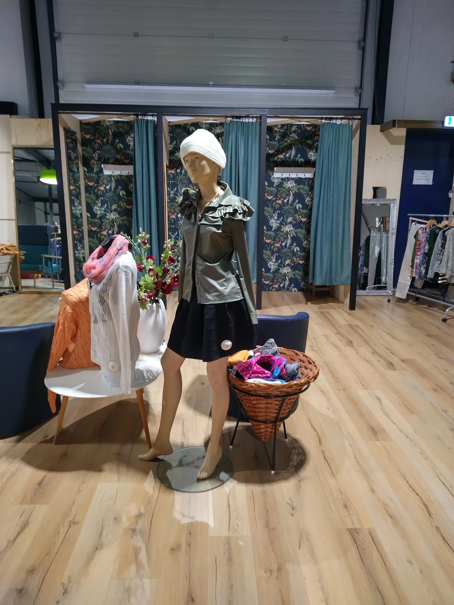 Etalage met kledingmanequin in zwart-wit outfit en mand met gekleurde kleding