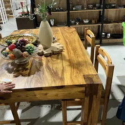 Houten eettafel met stoelen, fruitschaal en witte vaas als decoratie