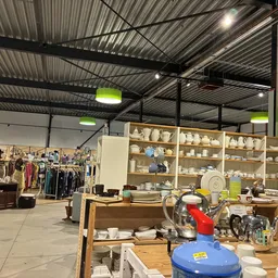 Winkelvloer met huishoudelijke artikelen, servies op stellingen en kledingrekken in een kringloopwinkel