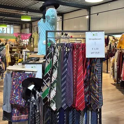 Rekken met stropdassen en sjaals, waaronder een display met prijskaart van €1,00