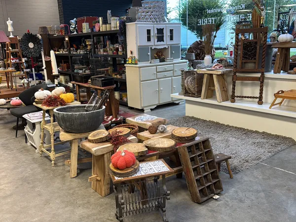 Winkelvloer met diverse meubels en huishoudartikelen uitgestald, waaronder houten tafels, kastjes en decoratieve items