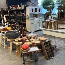 Winkelvloer met diverse meubels en huishoudartikelen uitgestald, waaronder houten tafels, kastjes en decoratieve items