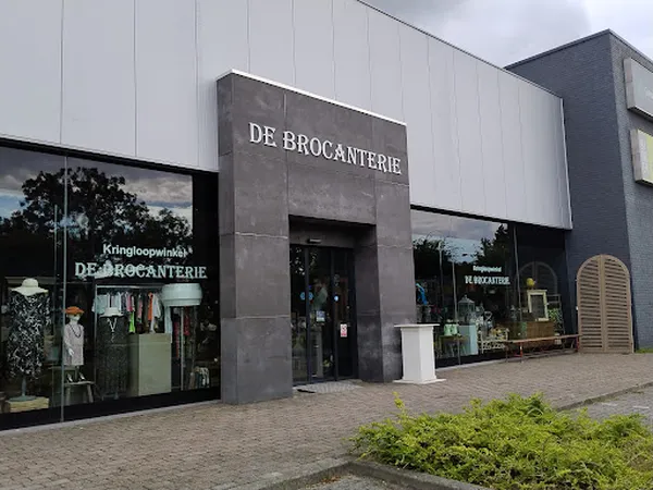 Voorgevel van kringloopwinkel De Brocanterie met donkergrijze entree en grote ramen, winkelnaam duidelijk zichtbaar