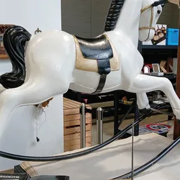 Wit decoratief paard met zwarte manen en een zadeltuig, close-up van een meubel- of decoratiestuk.