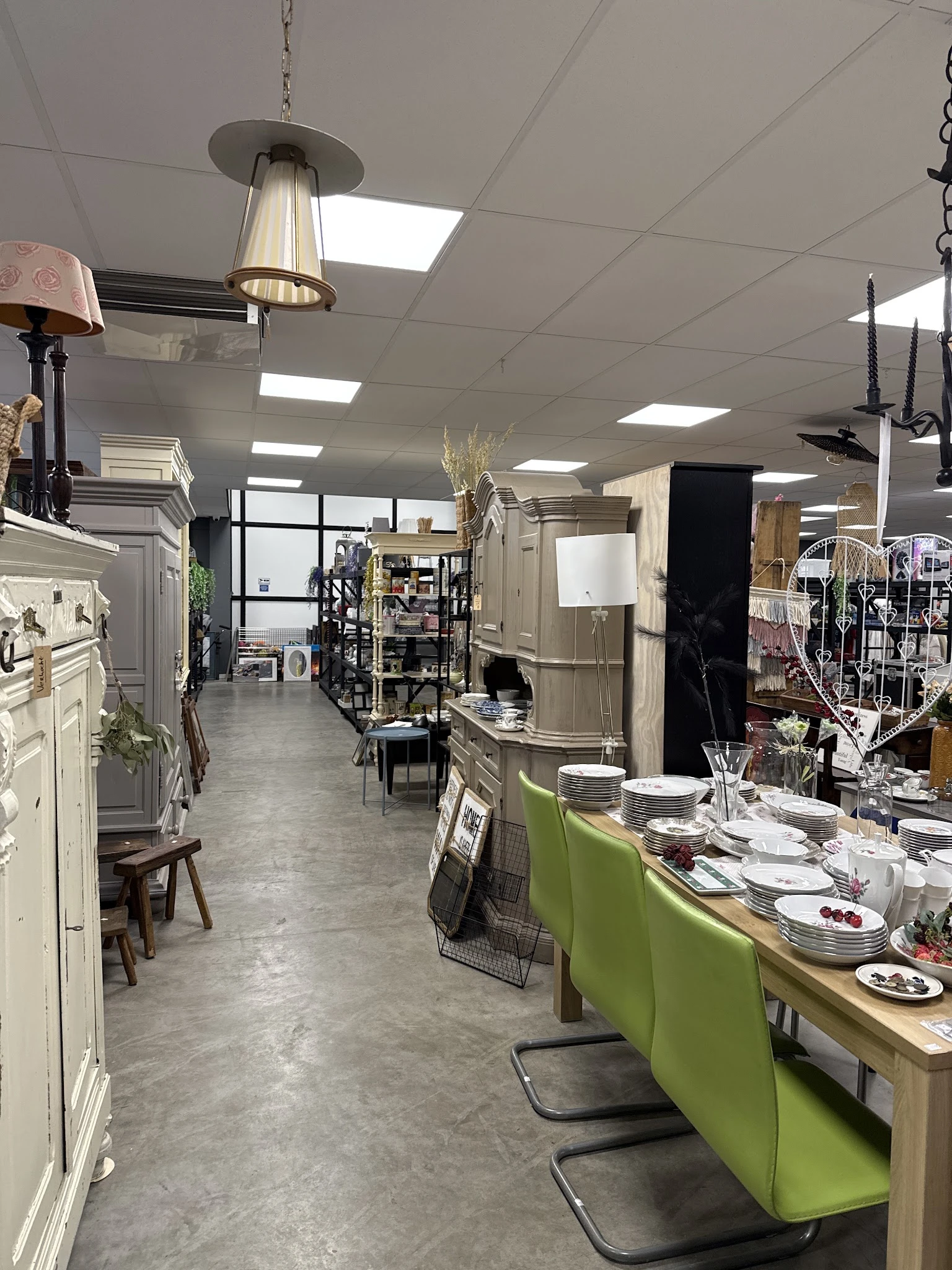 Winkelvloer van kringloopwinkel met diverse meubels, serviesgoed, lampen en huishoudartikelen uitgestald