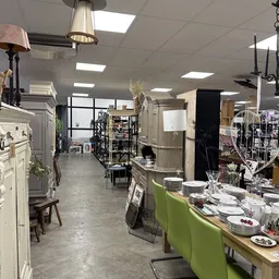 Winkelvloer van kringloopwinkel met diverse meubels, serviesgoed, lampen en huishoudartikelen uitgestald