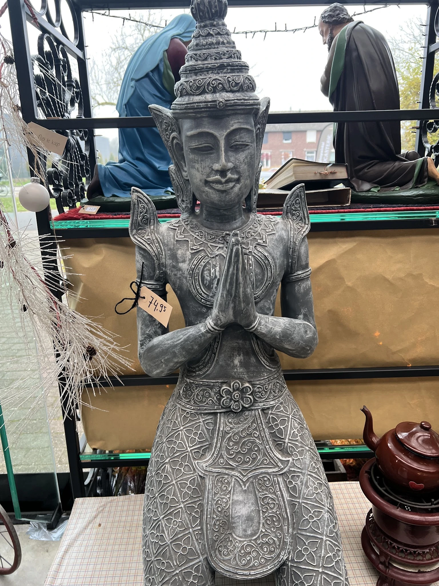 Grijzen stenen Boeddha-beeld in meditatiehouding met gedetailleerde kleding en sieraden