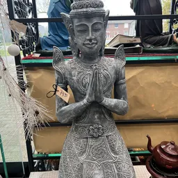 Grijzen stenen Boeddha-beeld in meditatiehouding met gedetailleerde kleding en sieraden