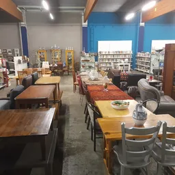 Winkelvloer met diverse meubels: houten eettafels, stoelen, kasten en boekenkasten tegen blauwe wanden