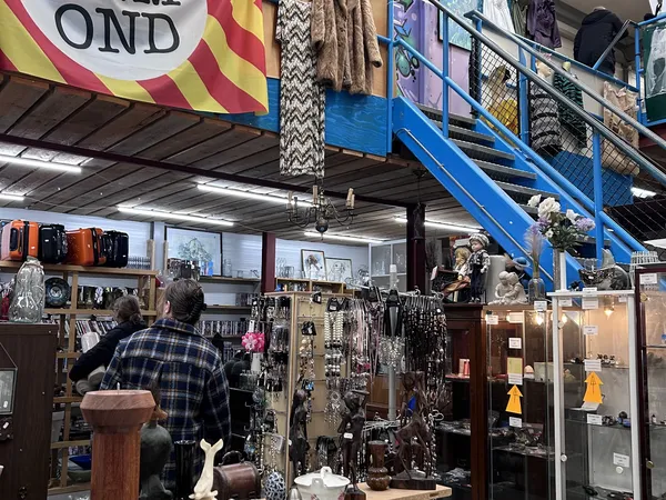 Winkelvloer met diverse artikelen, vitrines en stellingen vol spullen in kringloopwinkel