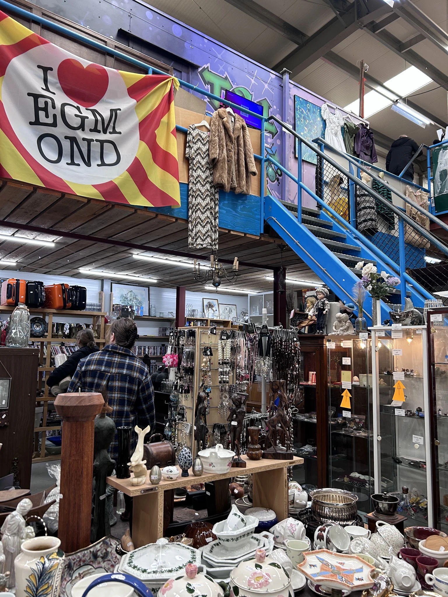 Winkelvloer met diverse artikelen, vitrines en stellingen vol spullen in kringloopwinkel