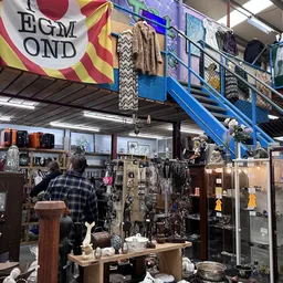 Winkelvloer met diverse artikelen, vitrines en stellingen vol spullen in kringloopwinkel