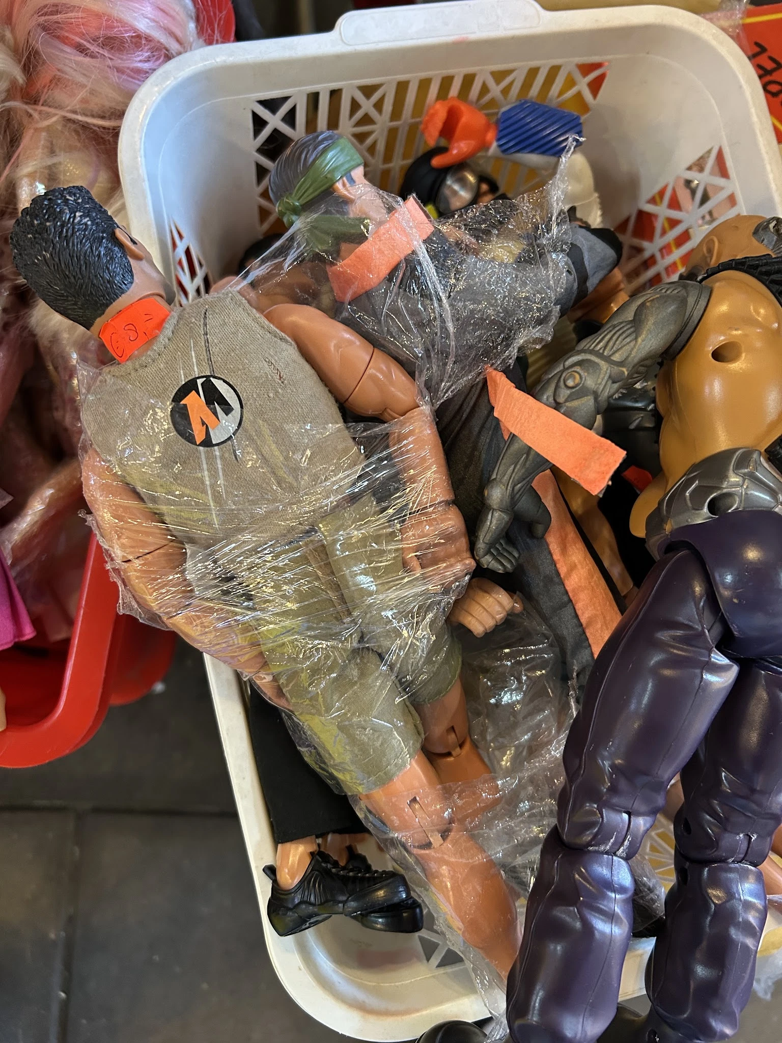 Diverse tweedehands speelgoed en plastic artikelen in plastic verpakking op een stapel