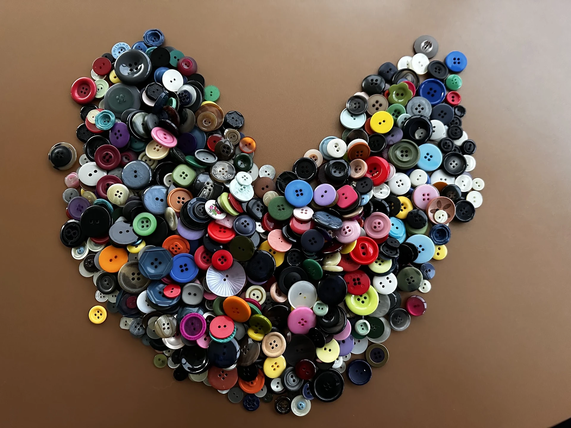 Hartvorming arrangement van gekleurde knoppen in verschillende maten en kleuren op neutrale achtergrond