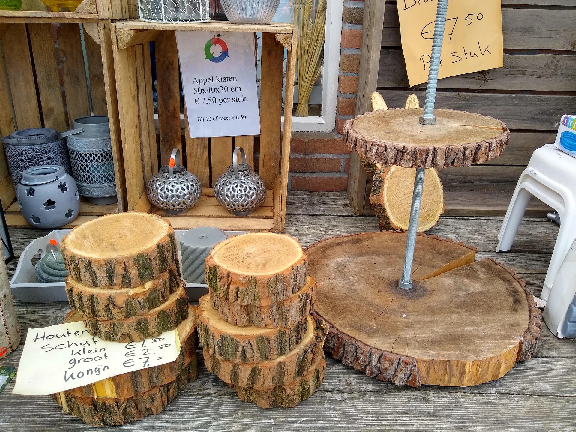 Uitgestalde houten schijven en boomschijven met prijskaartjes op een terras