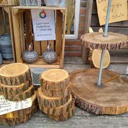 Uitgestalde houten schijven en boomschijven met prijskaartjes op een terras