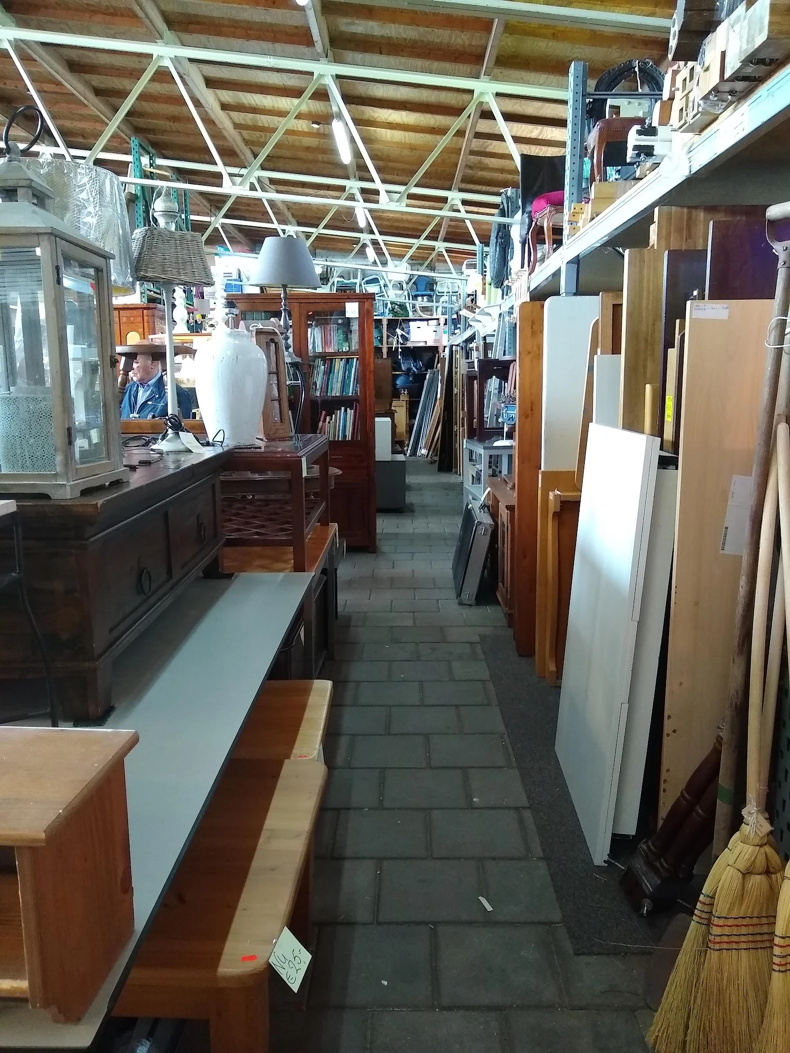 Binnenaanzicht van kringloopwinkel met schappen, boeken, meubels en diverse tweedehands artikelen langs de wanden