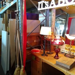 Rode vintage lampen en decoratieve items op een houten tafel in een kringloopwinkel