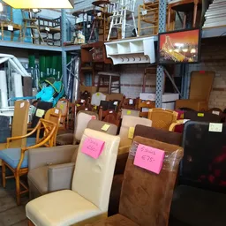 Eetkamerstoelen en zetels met prijsstickers op een rij in een kringloopwinkel