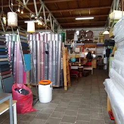 Winkelinterieur met textielen op hangers, stellingen met spullen en een roze afvalbak
