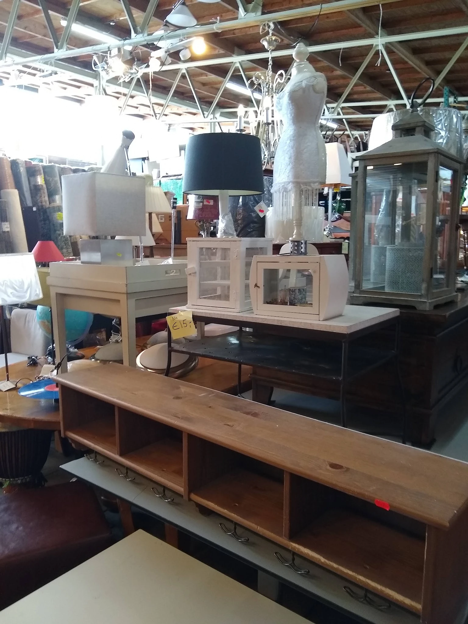 Tweedehands meubels en huishoudelijke artikelen uitgestald in de winkel, waaronder kasten, lampen en een houten dressoir