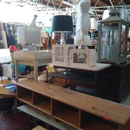 Tweedehands meubels en huishoudelijke artikelen uitgestald in de winkel, waaronder kasten, lampen en een houten dressoir