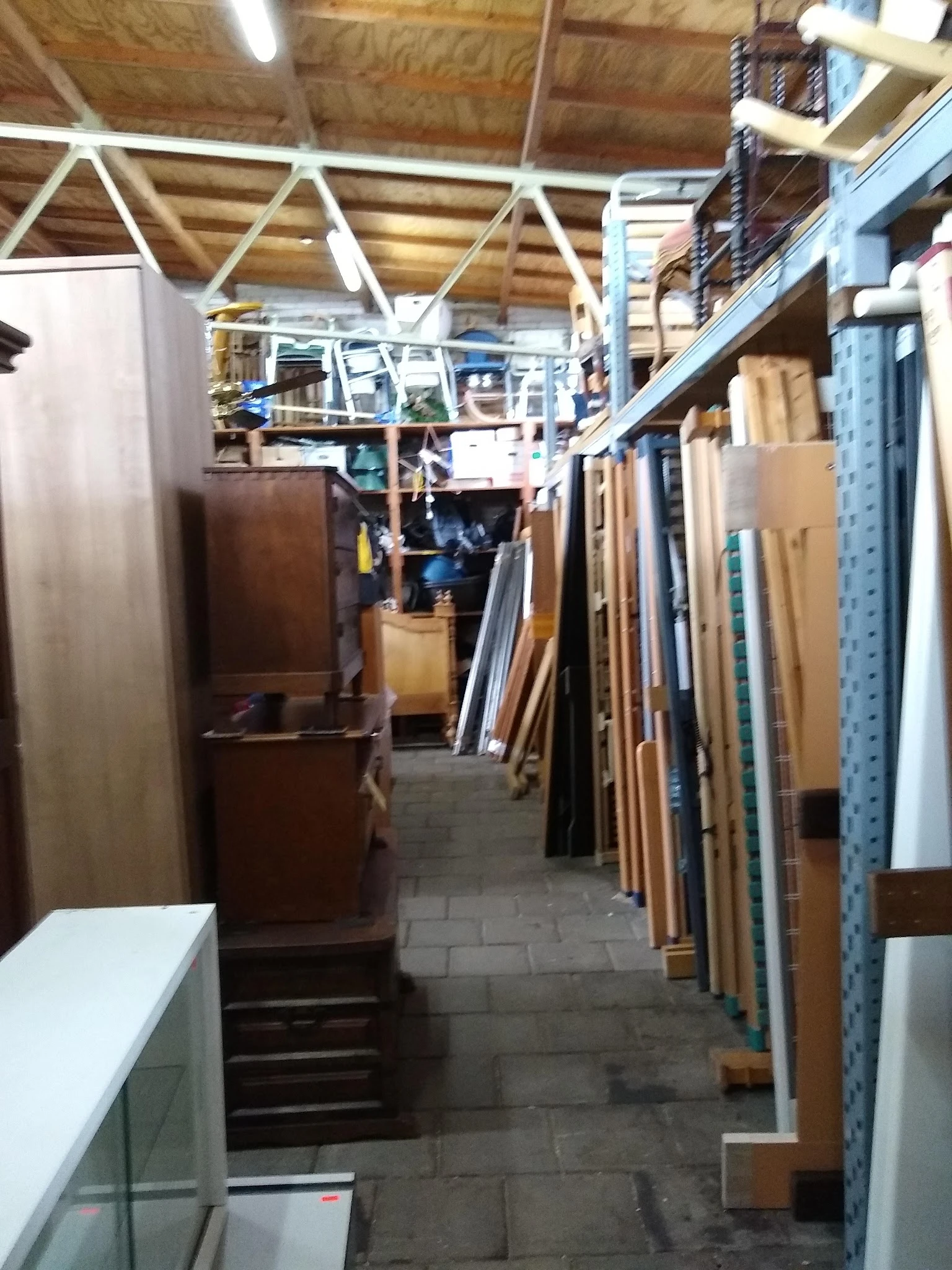 Smalle winkelgang met houten meubels en materialen tegen de wanden