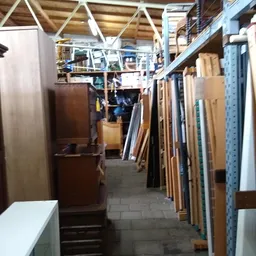 Smalle winkelgang met houten meubels en materialen tegen de wanden