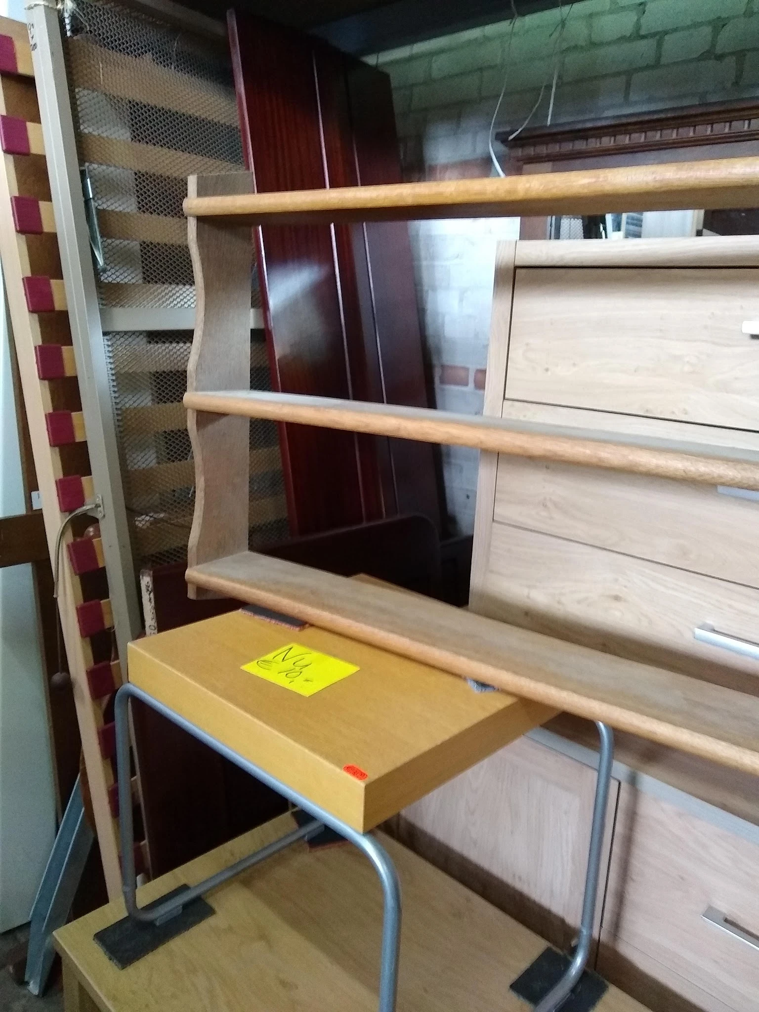 Houten wandplank met twee niveaus, geel doosje erop, tegen witte kastenwand.