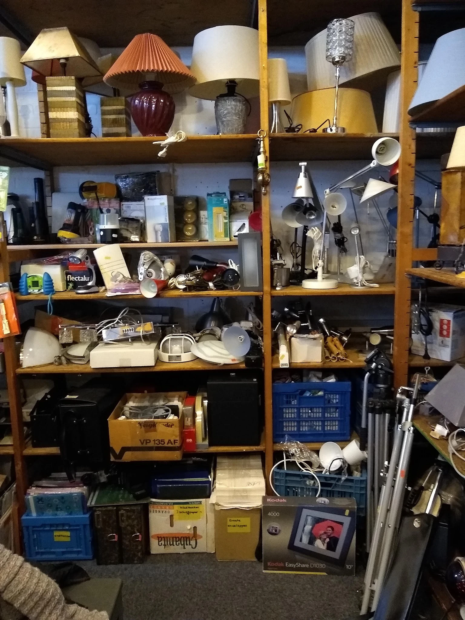 Houten stellingkast met diverse gebruikte huishoudelijke artikelen en elektronische apparaten