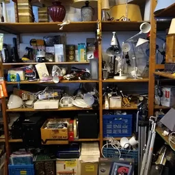 Houten stellingkast met diverse gebruikte huishoudelijke artikelen en elektronische apparaten