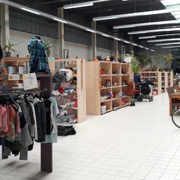 Winkelinterieur met houten stellingen, kleding op rekken, huishoudartikelen en diverse tweedehands spullen