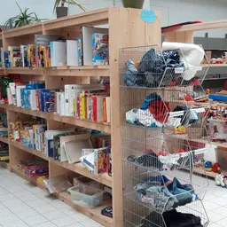 Houten kasten met boeken en speelgoed, metalen stellingen met speelgoedkisten in kringloopwinkel
