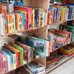 Houten stellingen met grote verzameling tweede hands bordspellen en puzzels, netjes uitgestald in dozen