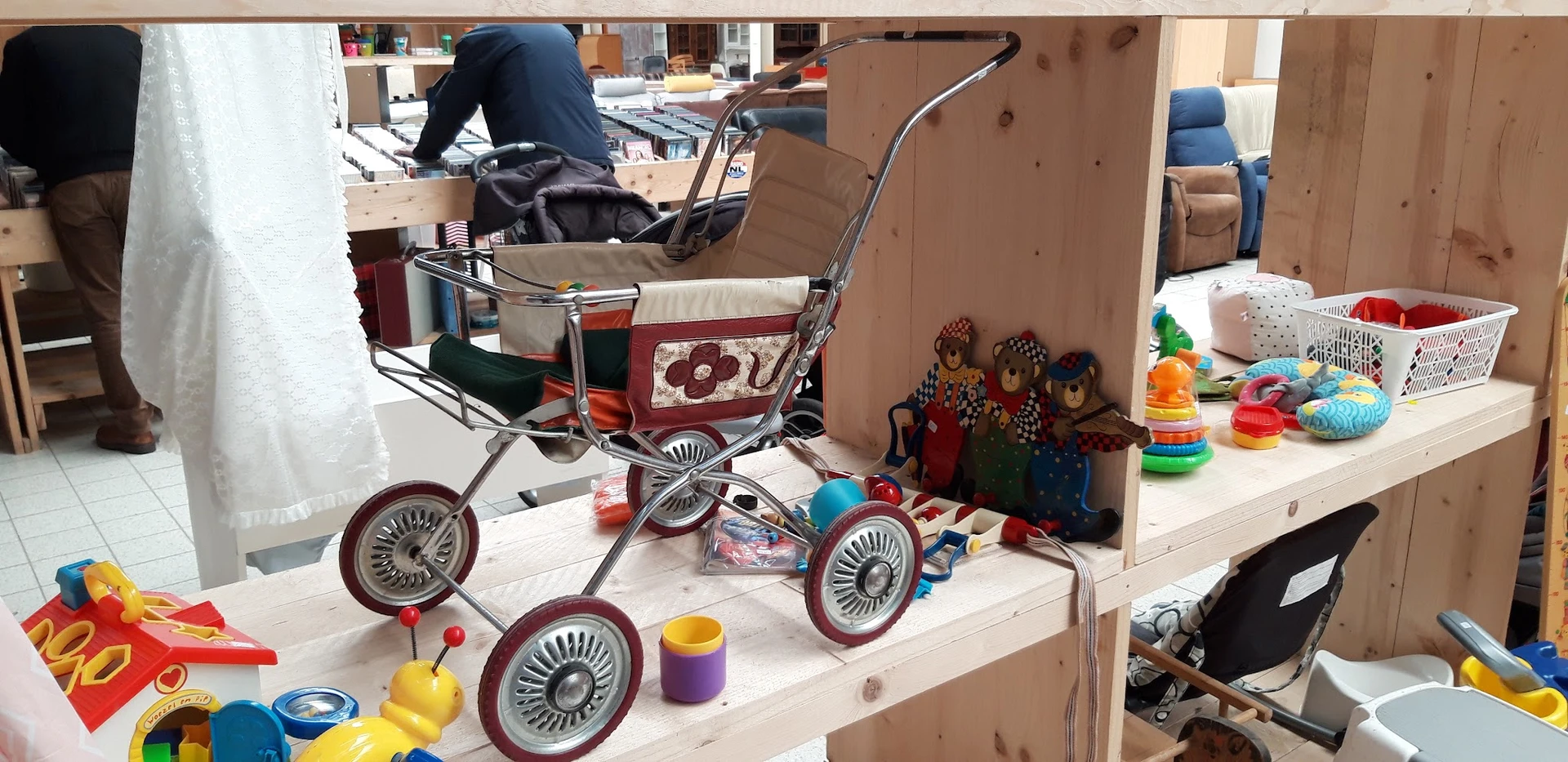 Kinderspeelgoed en vintage kinderwagens uitgestald op tafels in de winkel