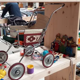 Kinderspeelgoed en vintage kinderwagens uitgestald op tafels in de winkel