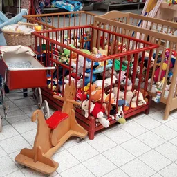 Verschillende babybedhjes en wiegjes in verschillende kleuren (rood, naturel, blauw) met speelgoed en beddengoet.