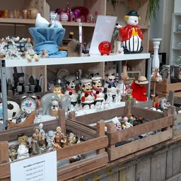 Uitgestalde verzameling decoratieve items en beeldjes in houten bakken en op schappen