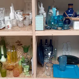 Kast met gesorteerde huishoudartikelen: glazen flesjes, cosmeticaproducten, blauwe decoratievoorwerpen en diverse voorraden o